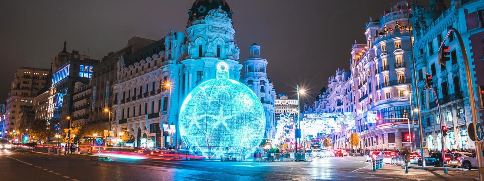 A main intersection in a Spanish city illuminated by festive, blue Christmas lights